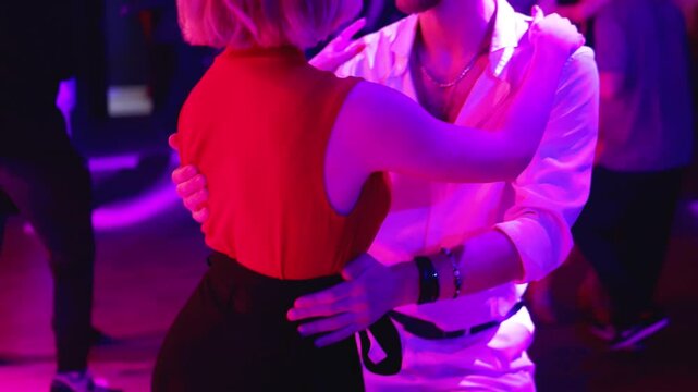 Couples dancing traditional latin argentinian dance milonga in a ballroom, tango salsa bachata kizomba lesson in red and purple lights, performance rehearsal, evening dance school class festival