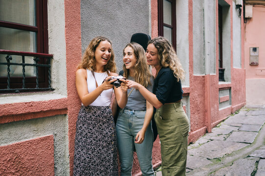 Musicians laughing while watching photos on vintage camera in alley