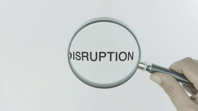 Disruption word or text highlighted by a magnifying glass in a hand on a white background, symbolizing innovation, change, and transformation