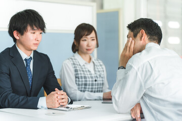 窓口で落ち込む顧客の相談に乗るビジネスマン（困る・ショック・借金・倒産・自己破産）
