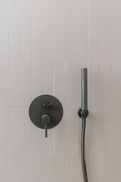 Modern hower setup with dark matte fixtures against white tiled wall