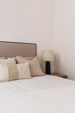 A minimalist bedroom with multiple beige and cream pillows