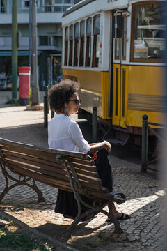 Woman sitting on bench waiting for tram 28 in Lisbon