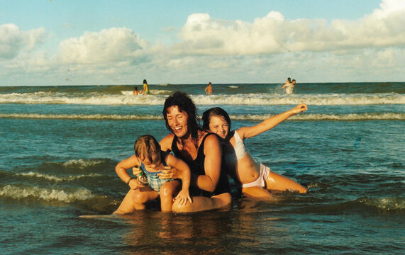 Happy family, mother and children on beach at sea