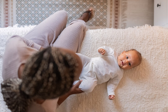 Parent playing with happy newborn on bed