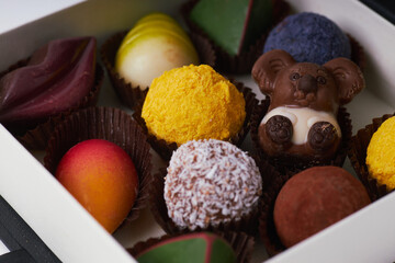 Luxury assorted chocolates and truffles in an elegant black gift box with copy space on white background  
