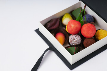Luxury assorted chocolates and truffles in an elegant black gift box with copy space on white background  
