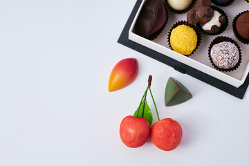 Luxury chocolate assortment in an elegant gift box with decorative cherries and gourmet sweets on a white background  

