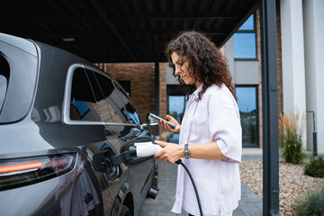 A woman connects a charger to an electric car