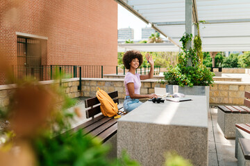 Woman waving while studying outdoors
