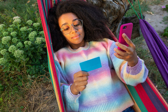 beautiful African American girl with glasses lies in a hammock