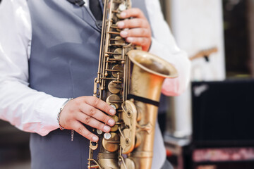 Fototapeta premium Concert view of saxophonist musician, saxophone sax player with vocalist and musical band during jazz orchestra show performing music on a stage in the scene lights, concert in a musical club hall
