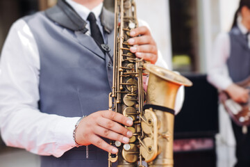 Obraz premium Concert view of saxophonist musician, saxophone sax player with vocalist and musical band during jazz orchestra show performing music on a stage in the scene lights, concert in a musical club hall