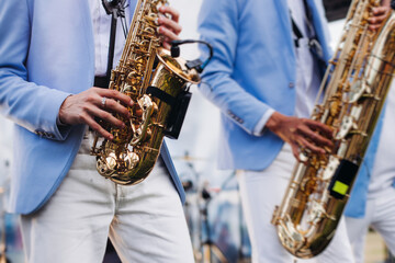 Obraz premium Concert view of saxophonist musician, saxophone sax player with vocalist and musical band during jazz orchestra show performing music on a stage in the scene lights, concert in a musical club hall
