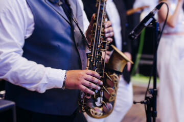 Concert view of saxophonist musician, saxophone sax player with vocalist and musical band during jazz orchestra show performing music on a stage in the scene lights, concert in a musical club hall