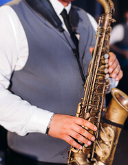 Obraz premium Concert view of saxophonist musician, saxophone sax player with vocalist and musical band during jazz orchestra show performing music on a stage in the scene lights, concert in a musical club hall