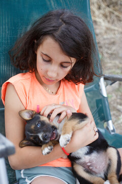  kid holding little puppy in her arms in a summer day
