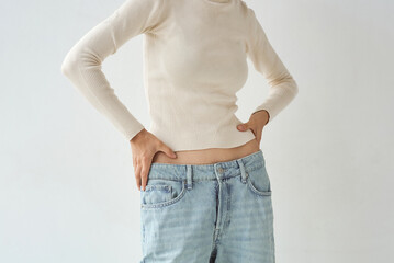Woman models oversized jeans with a sweater in a minimalist studio