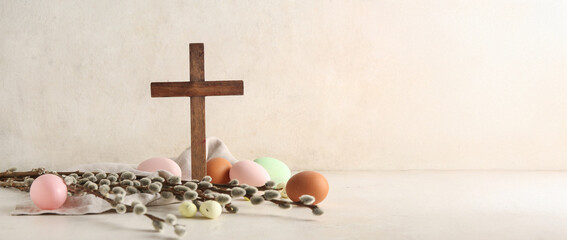 Wooden cross, pussy willow branches and painted Easter eggs on light background with space for text © Pixel-Shot