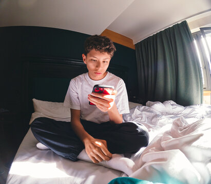 Teen Relaxing with Phone in Bunk