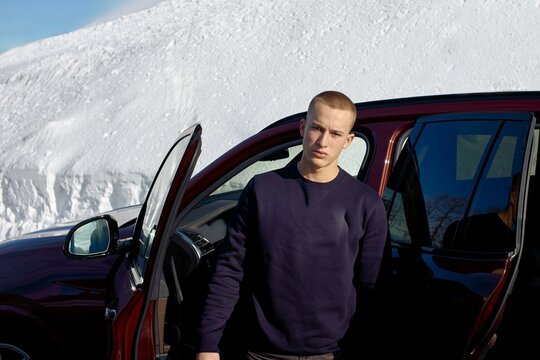 Young man standing beside a car in snowy landscape