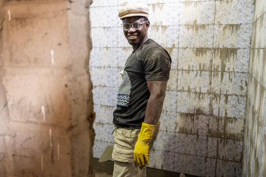 Smiling african bricklayer tiling bathroom in Senegal