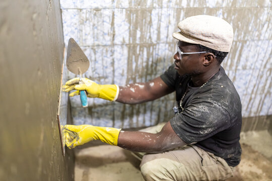 Bricklayer Placing Tiles on Bathroom Wall in Senegal