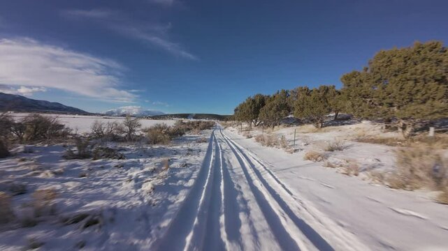 Aerial-FPV-First person view- Flying low and fast over tire tracks on snowy country lane road