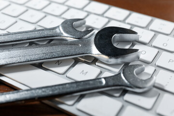 Fototapeta premium Technical support concept. Wrenches and keyboard on wooden background, closeup