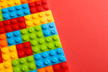 Construction toy. Colorful building bricks on red background, above view with space for text