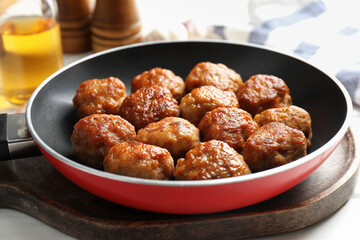 Tasty meatballs in frying pan on white table, closeup