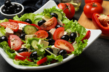 Delicious fresh Greek salad on black table, closeup
