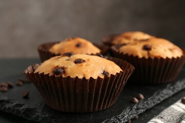 Delicious muffin with chocolate chips on table, closeup