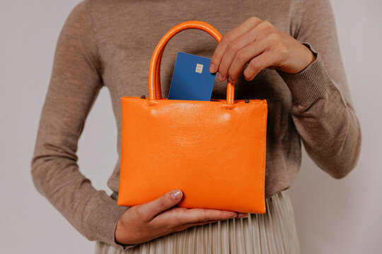 Woman putting credit card in orange purse, ready for shopping