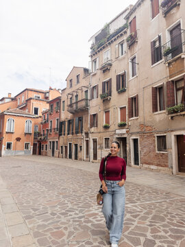 Fototapeta Tourist woman walking down a wide, empty street in Venice, Italy.