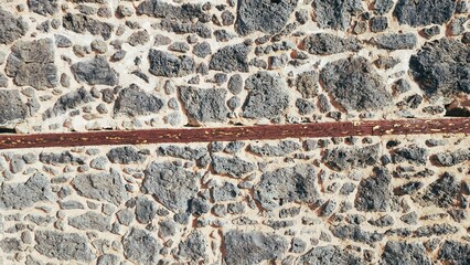 The walls of an old building made of piles of stones and wood stuck together with mud.