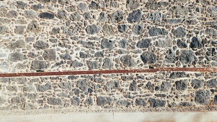 The walls of an old building made of piles of stones and wood stuck together with mud.
