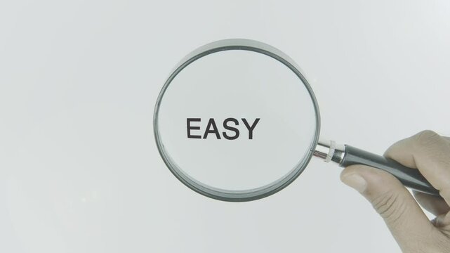 Easy text or word highlighted by a magnifying glass in a hand on a white background, symbolizing simplicity and accessibility