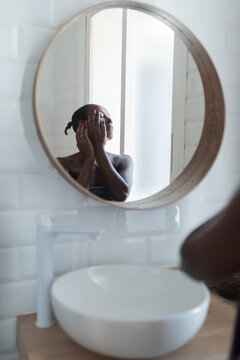 Woman applying cream on her face in bathroom