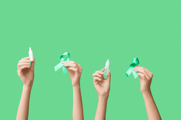 Female hands with ribbons and eye drops on green background. Glaucoma awareness concept