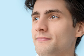 Young man with brown eyes on blue background, closeup. Glaucoma awareness month