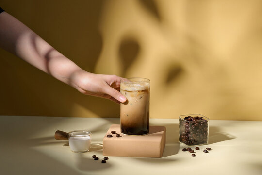 Hand Reaching for Refreshing Iced Coffee on Minimalist Table