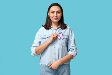 Pretty young woman with light purple ribbon on blue background. Testicular cancer awareness concept