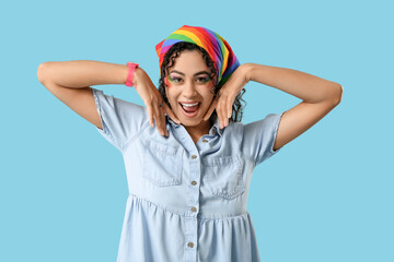 Happy African-American woman with rainbow headscarf on blue background. LGBT concept
