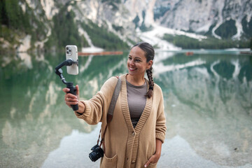 woman using mobile phone at braies lake in the dolomites