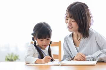 勉強する女の子と見守る母
