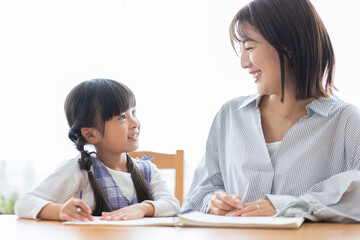 勉強する女の子と見守る母