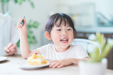 部屋のテーブルでケーキを食べる親子
