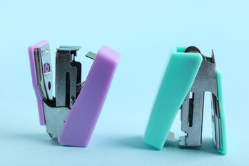 Different small staplers on blue background
