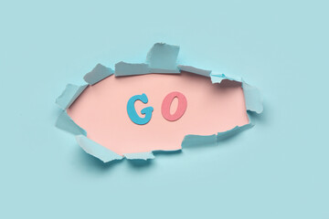 Word GO visible through torn paper on blue background. Top view